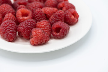 Raspberry  in white plate on white background with copy space.
