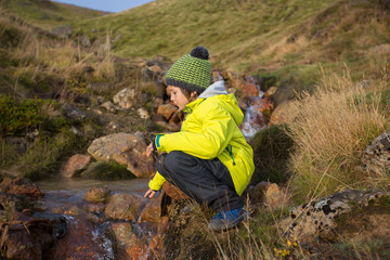 Child playing on a pond in geothermal area in Krysuvik on early sunny morning, Southern Peninsula (Reykjanesskagi, Reykjanes Peninsula), Iceland