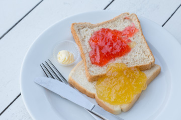 Strawberry and orange jam on the bread with white wood table
