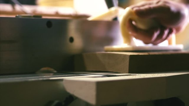 Close-up male hands using a professional wood jointer machine in a woodworking shop