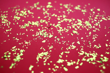 Golden confetti on red background, blurred, holiday concept