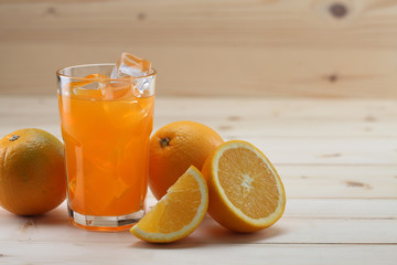 Orange Juice glass on wooden background. Pieces of orange fruit along with the glass.