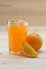Orange Juice glass on wooden background. Pieces of orange fruit along with the glass.