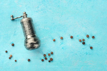 Allspice, Jamaican pepper. Black peppercorns with a vintage pepper mill, overhead shot on a blue...