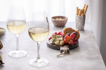 Fototapeta na wymiar Charcuterie board with different snacks for wine. Blue cheese, olives, baguette slices, cured meat and grapes Wine snacks set background.