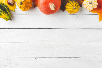 Autumn composition with frame made of colourful leaves and pumpkins on white wooden background. Top...