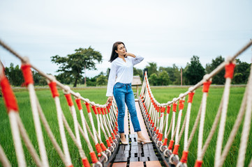 Fototapeta na wymiar A happy woman on a wooden bridge in a green meadow on a sunny day. Happy, health, travel, lifestyle concept