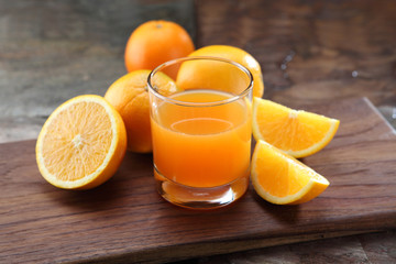 Orange Juice glass on a stone background along with the fresh fruit pieces.