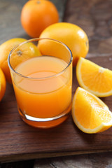 glass of orange juice and oranges on stone background