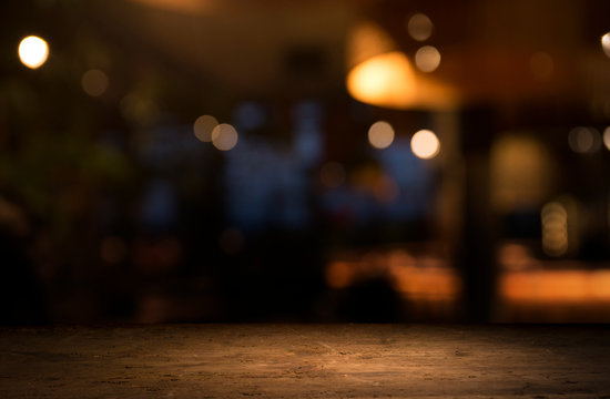 Empty wood table top on blur light gold bokeh of cafe restaurant in dark background