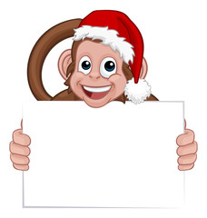 A Christmas monkey animal cartoon character in a Santa hat holding a sign