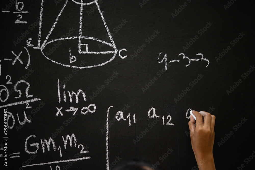 Wall mural The hand that writes the formula with white chalk on the blackboard