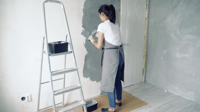 Woman worker using a spatula applying decorative plaster in the apartment or house. Construction, repair and renovation