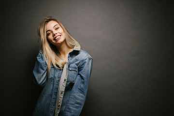 Fashion portrait of a sexy blonde woman with a make up wearing jeans clothes over gray background