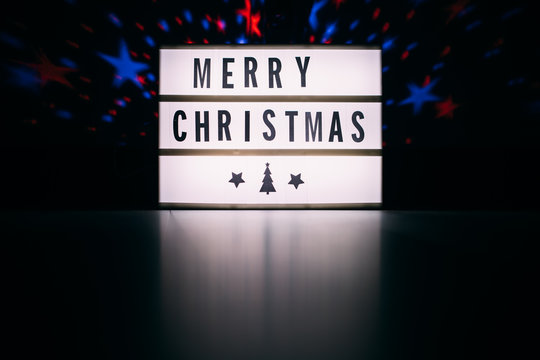Merry christmas sign in lightbox in the dark room interior with space for text