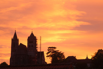 Church on hill with scaffolding due to restoration under orange evening  sky (Breisach, Baden, Germany)