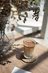 Iced coffee latte with brown upper layer coffee and white lower layer fresh milk in glass on wooden table