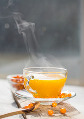 Sea buckthorn tea  in a glass cup before window.   Herbal vitamin beverage