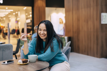 Cute plus size woman resting in cafe inside city mall