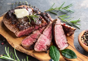 Poster Medium rare Ribeye steak with herbs and a piece of butter on the wooden tray. © volff