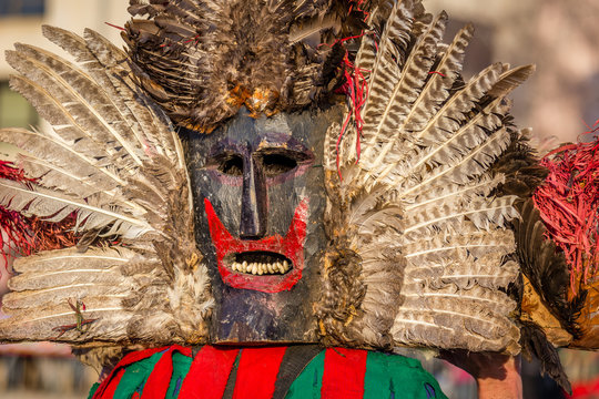 Mummers perform rituals to scare evil spirits at Surva festival at Pernik in Bulgaria. The people with the masks are called Kuker (kukeri). Wood mask with feathers and red mouth.