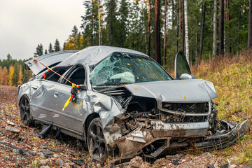 Totaly wrecked silver colored car in a ditch by the road