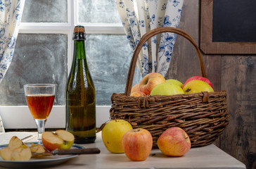 Bottle and glass of cider with apples. In rustic house