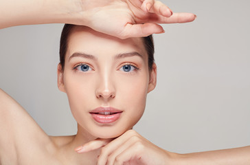 Sensual girl with brown hair clean fresh skin naked shoulders touches her face with both hands...