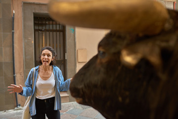  Spanish woman in the closures of San Fermin in front of a bull in a street.