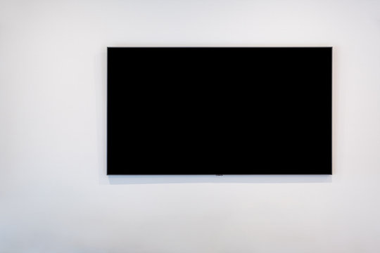 Black flat screen TV on white wall with copy space