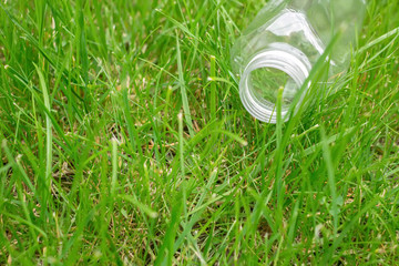 Empty plastic bottle on green grass. Ecology problem. Environmental pollution.	