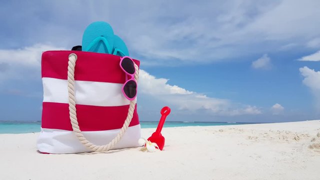 family vacation background, close up shot of pink white striped beach bag, sunglassesblue flip-flops plastic shovel and frangipani flower, copy space