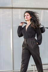 Black-haired girl. Stylish business woman. Black overalls. Suit and handbag. Shoes with heels.