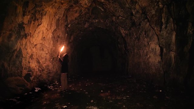 Speleologist exploring cave using a flame torch. 4k