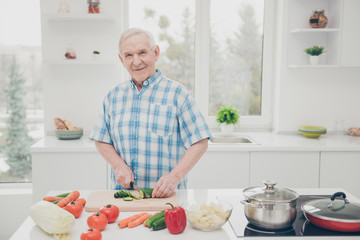 Portrait of his he one single nice attractive lovely cheerful cheery granddad cooking fresh delicious dishes in modern light white interior kitchen indoors