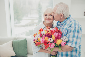 Portrait of her she his he two nice lovely cheerful cheery sweet tender people granny receiving big fresh floral tulips congrats greetings spring springtime in light white interior living-room house