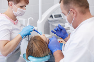 Doctor dentist treats teeth of a beautiful young girl patient. The girl on reception at the dentist. Doctor dentist treats tooth