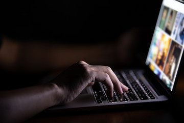 Hand of a man using laptop computer working at night