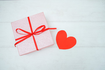 Gift box on the wooden background. Red ribbon and beautiful flower. Valentine's Day gift.