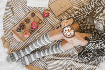 Woman with hot chocolate relaxing on bed