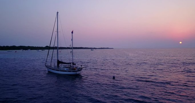 Beautiful sailing boat on purple sunset in tropical sea waters. aerial view drone tracking shot