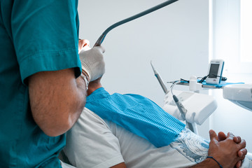 Italian people, medicine, stomatology and health care concept - dentist with patient talking at dental clinic office, during painless teeth cleaning done in a modern medical center. Rome, Italy, 2019.