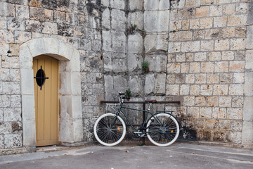 un vélo posé contre un mur de pierre et une porte en bois