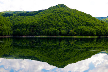 View of the high green hill, mountain. Reflection in water. Out of focus. A clear sunny day. Nature background.
