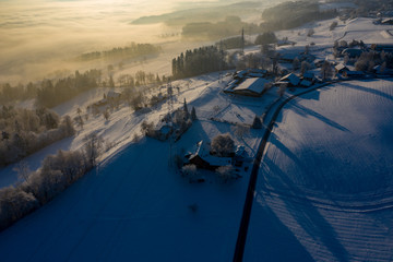 Winterlandschaft mit Sonnenaufgang im Nebel, in der Schweiz. Luftaufnahme