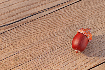Side view of an autumn brown beautiful acorn on a textured rustic wooden surface of a table or bench on a sunny day. Minimalism. Brown planks design template with copy space for text