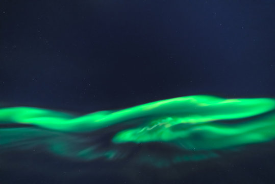 Vibrant northern lights in the starry night sky. Green aurora in dark. Image from Tromso, Norway.