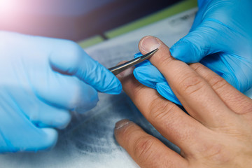 Manicurist cuts a cuticle on a man’s hand with scissors