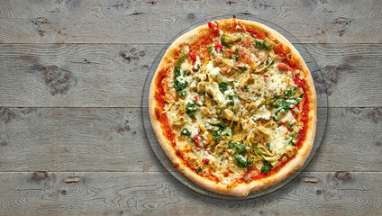 Textured wooden Table with vegetarian pizza on plate.