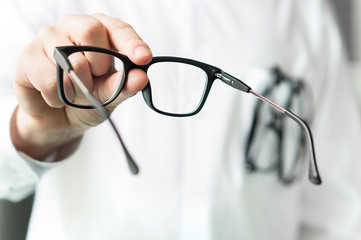 Optician giving new glasses to customer for testing and trying. Eye doctor showing patient lenses....